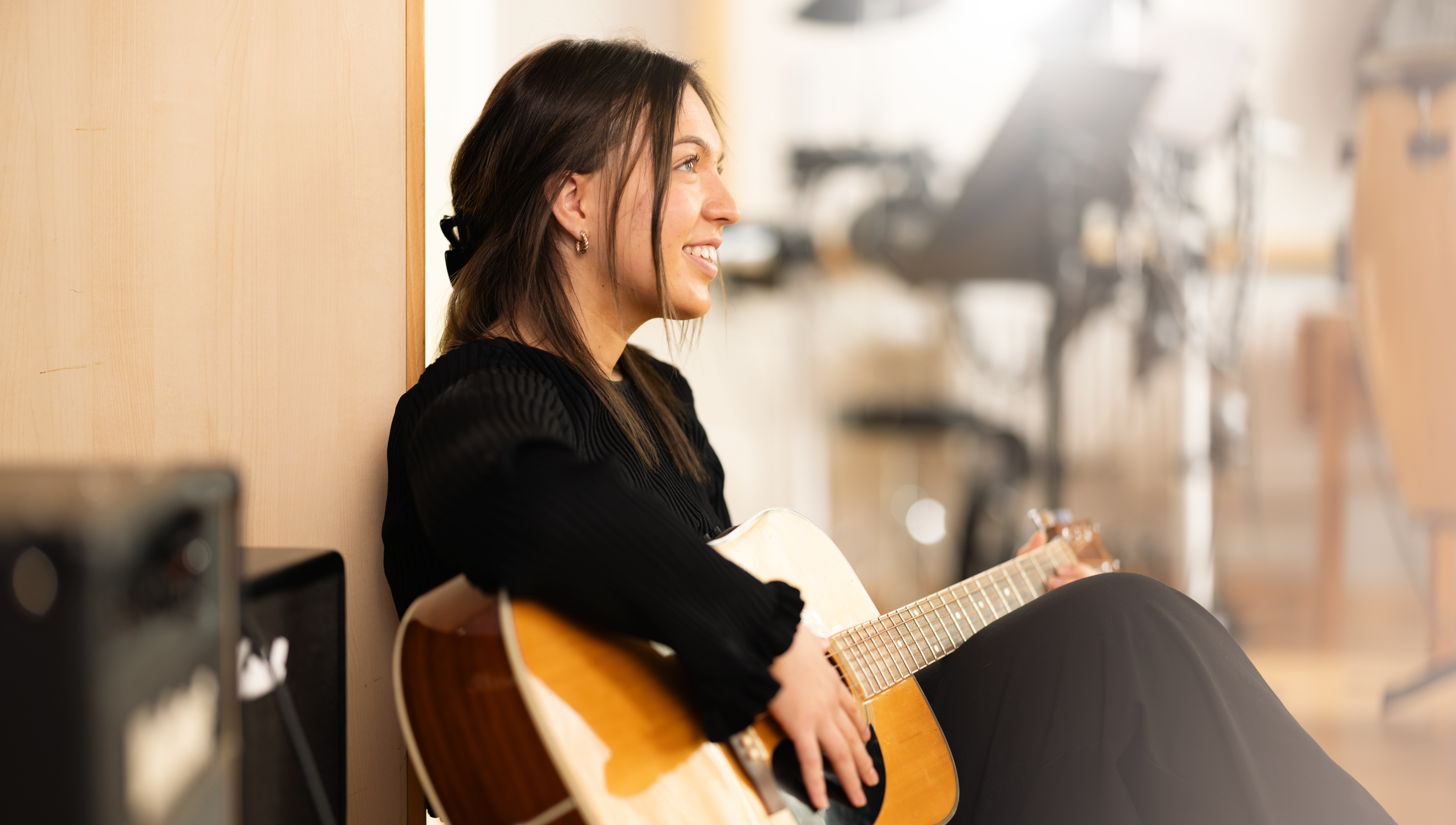 Leende tjej som sitter med en gitarr